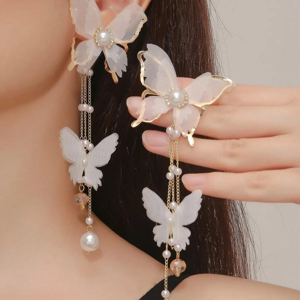 A pair of white butterfly-design earrings with pearl and rhinestone details on a tassel lace style.