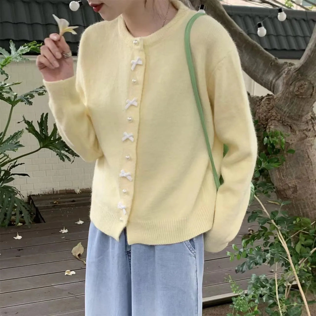 Women's light blue cashmere blend cardigan with white bow and pearl button detail on front.