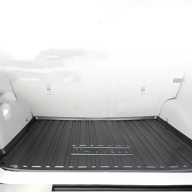 Black car boot liner with carbon fibre pattern texture, laid flat showing its tailored shape.