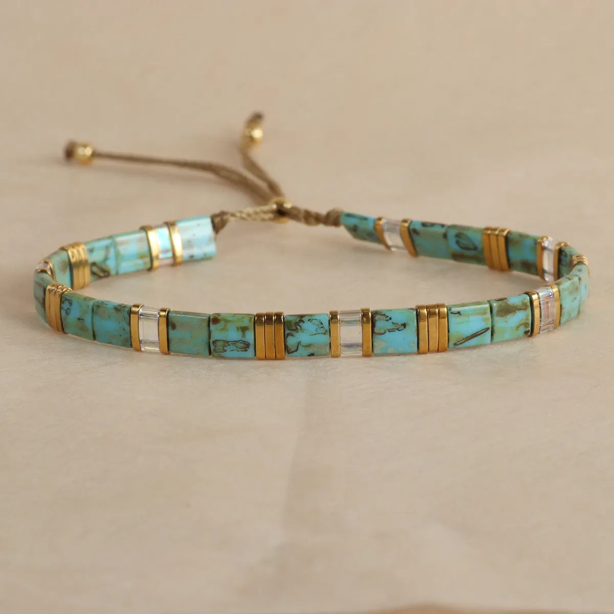 Adjustable geometric beaded bracelet with pull beads in milky white, black, green, blue or red.