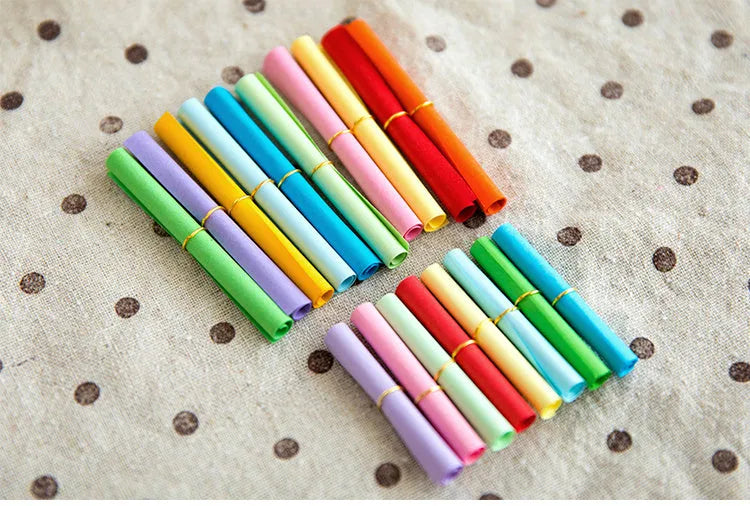 Assorted coloured mini paper scrolls for drift bottle messages with metal eyelets, shown in different sizes.