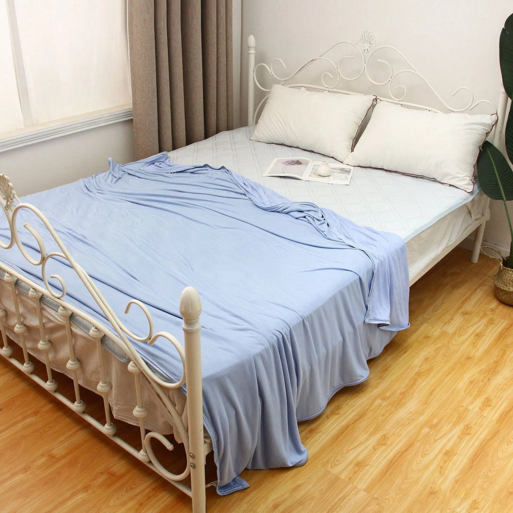 Blue and grey polyester cooling blanket with Japanese Q-Max fibres on a bed.