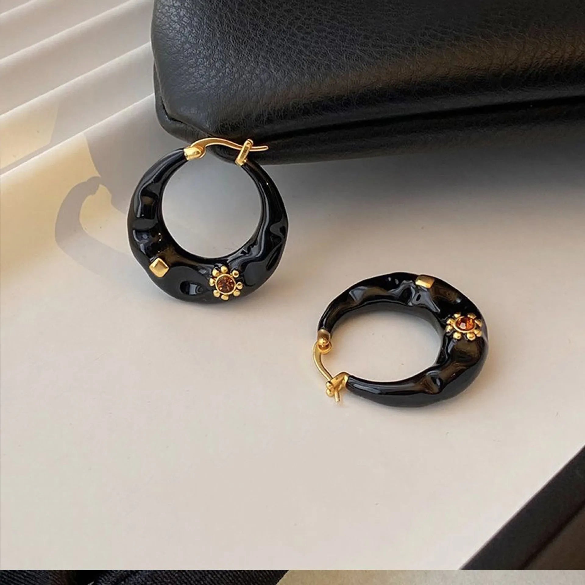 A pair of retro alloy ear studs with a dripping oil finish and black rhinestone detail.