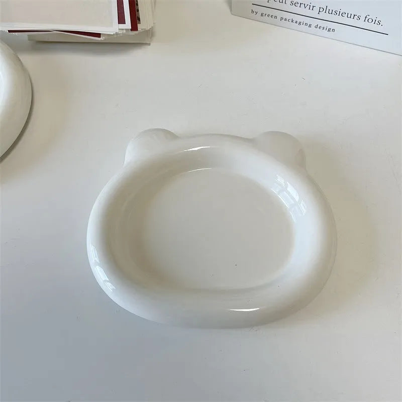 White porcelain plate with bear doodle design, shown as a plant pot tray.