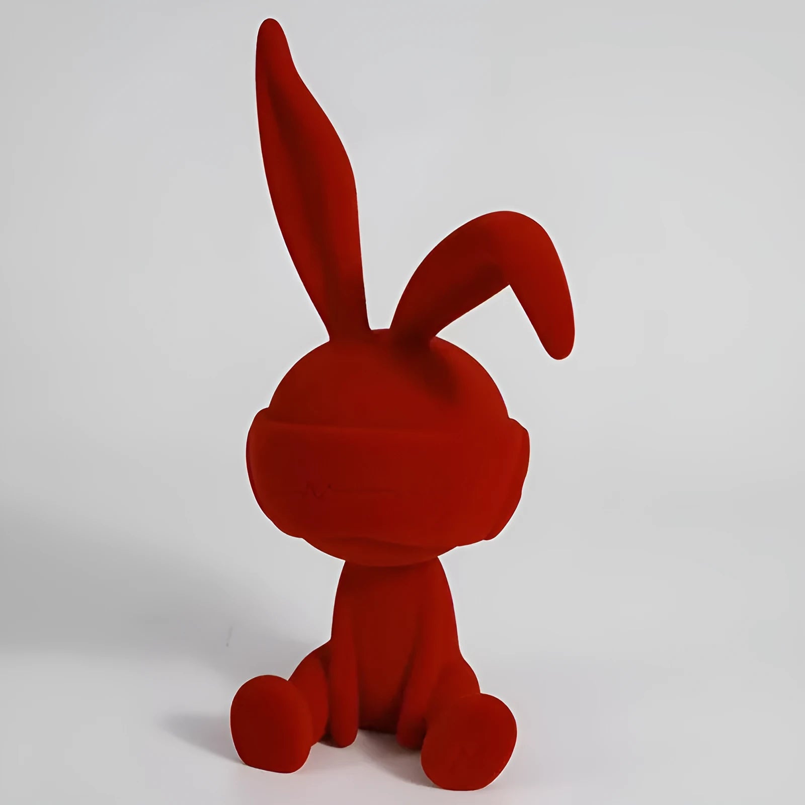 Small blue resin ornament of a rabbit wearing a blindfold on a wooden table.