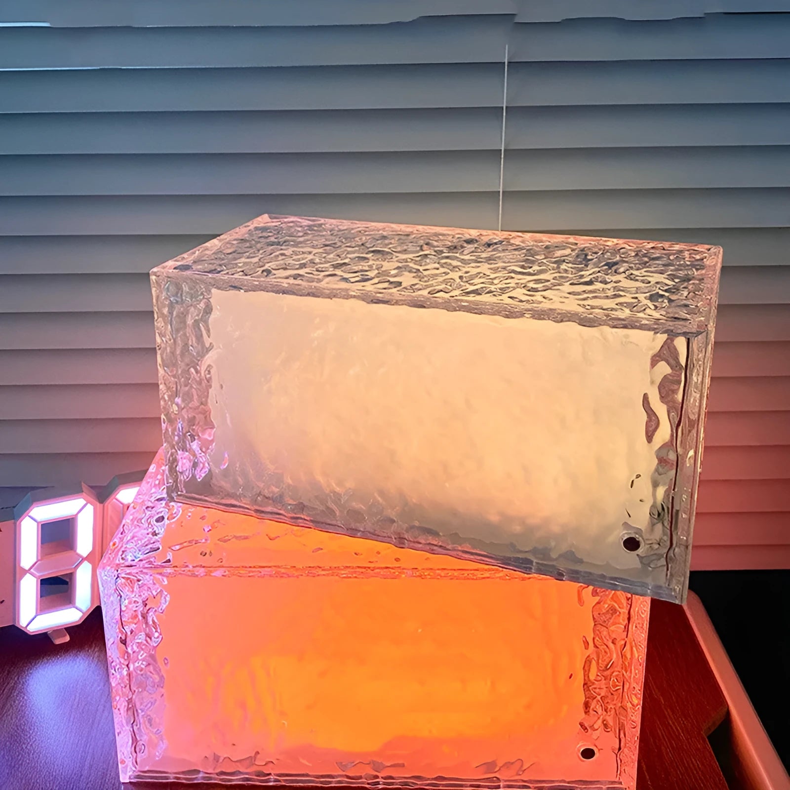 Geometric clear acrylic night light with remote control on a table.
