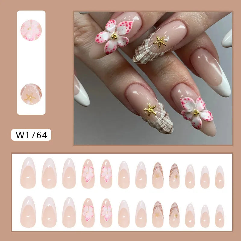 French style press-on fake nails with white tips and decorative pink rock-pattern floral patches on a clear nail bed.
