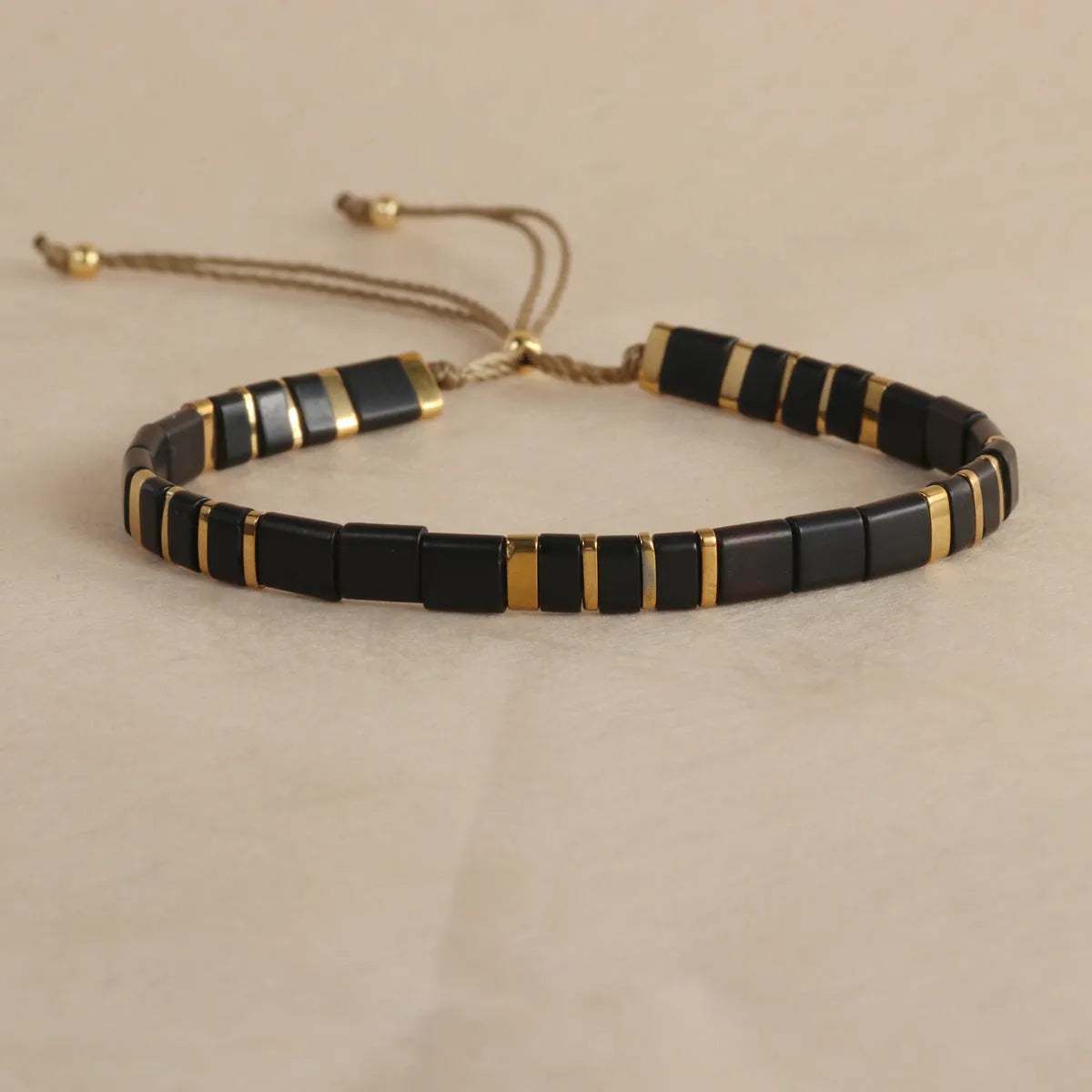 Adjustable geometric beaded bracelet with pull beads in milky white, black, green, blue or red.