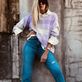 Loose lilac plaid print sweater with long sleeves and ribbed trim on a hanger.