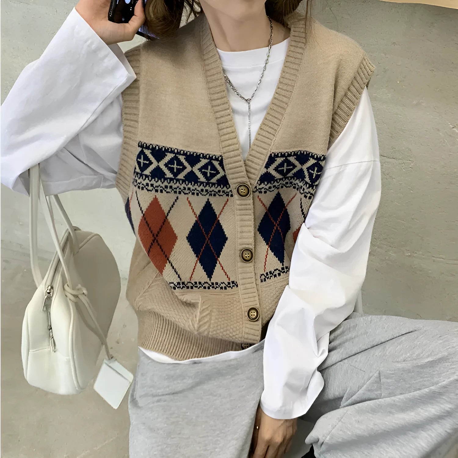 Woman wearing a khaki sleeveless cardigan with a diamond plaid pattern, loose fit.