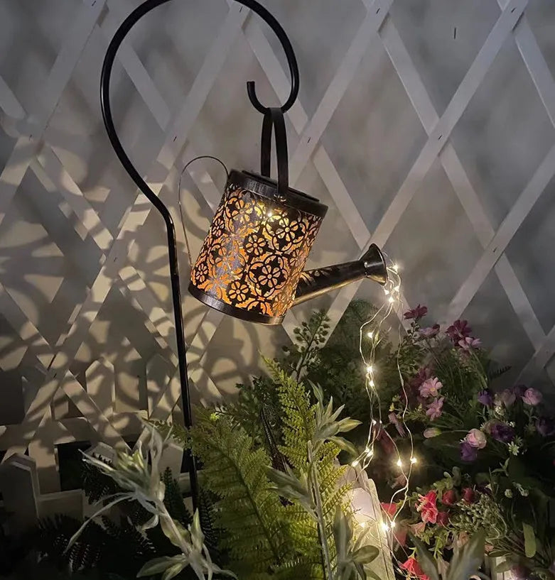 Solar watering can garden lamp with hollow-out iron shower body and 36 warm white LED lights on copper wire, installed in grass