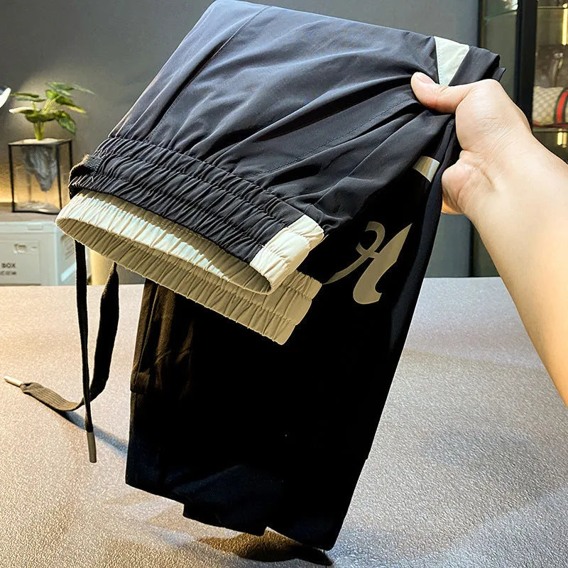 Men's solid black cropped trousers with banded ankles made from ultra-thin ice silk and cotton blend fabric.