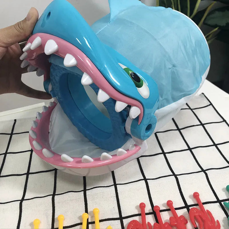 Great white shark tricky toy with small plastic fish inserted in its mouth on a tabletop