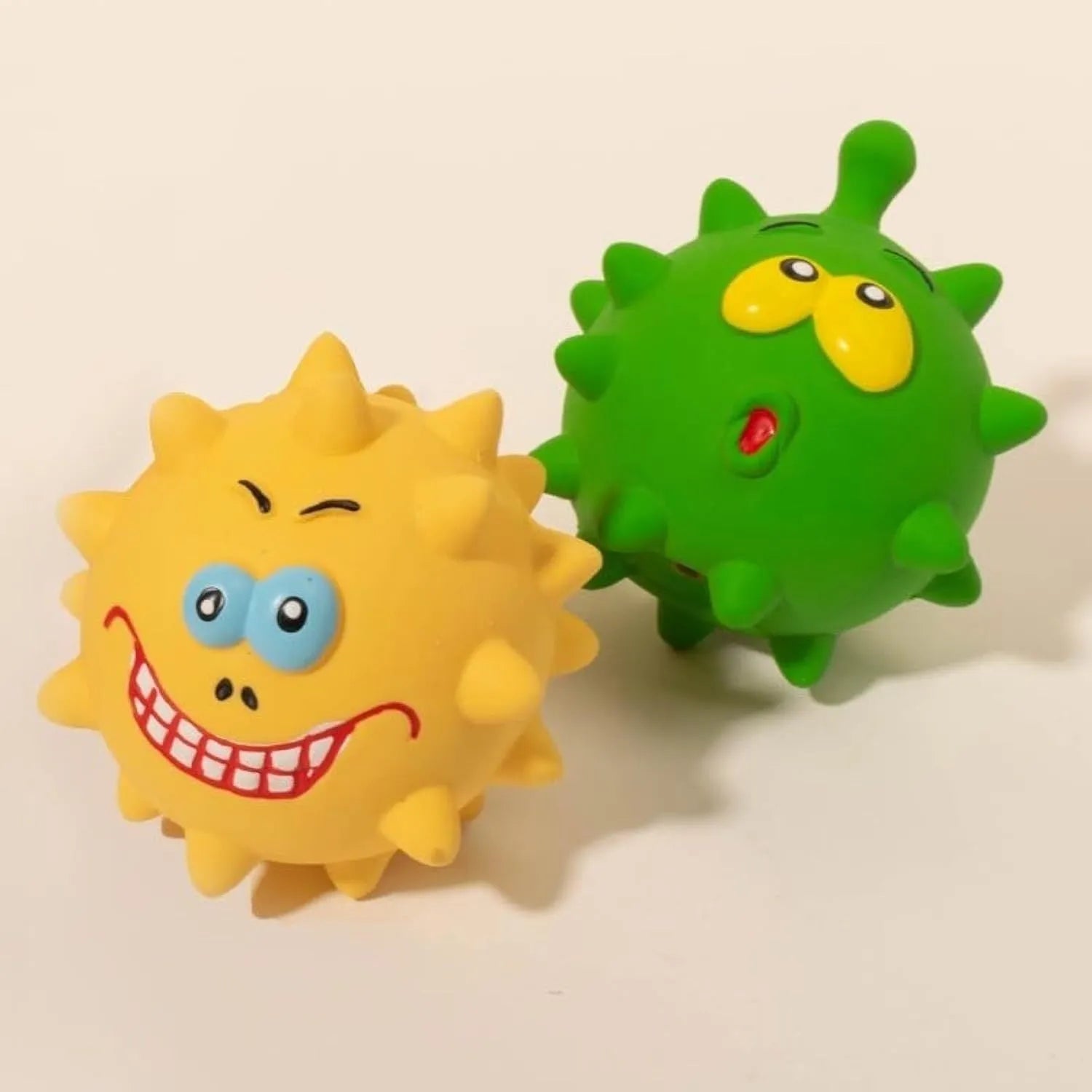 Four colourful natural latex squeaky dog toy balls with cute faces on a blue background.