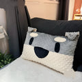 Grey schnauzer and white West Highland puppy decorative throw pillows on a sofa.