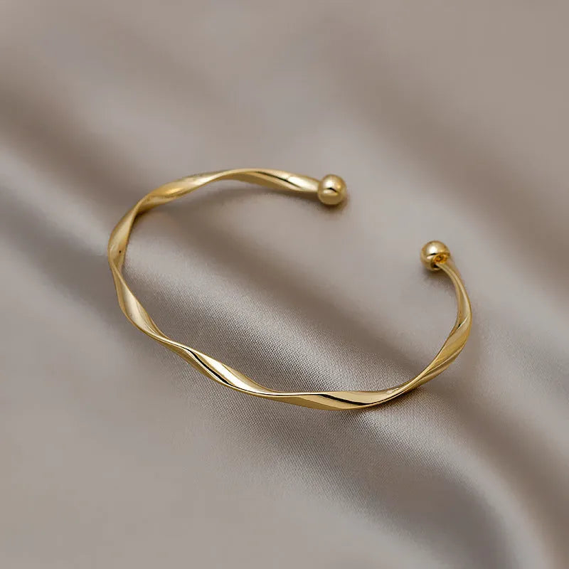 Gold alloy geometric twist bracelet with 6.2 cm inner ring diameter on white background