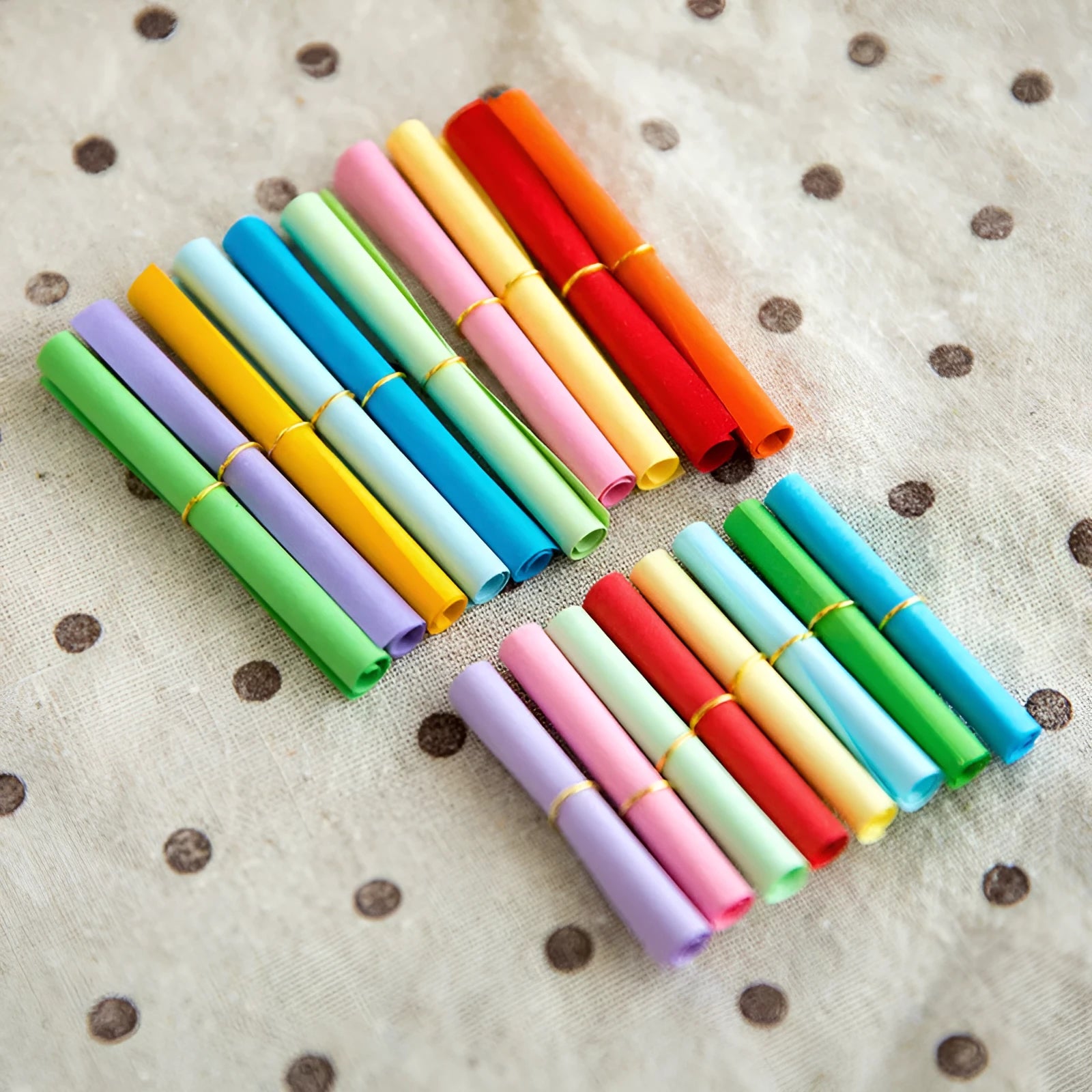 Assorted coloured mini paper scrolls for drift bottle messages with metal eyelets, shown in different sizes.