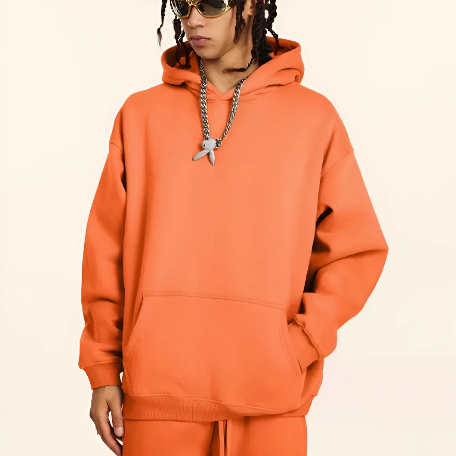 Man wearing a loose-fitting grey hooded cotton sweater with drop-shoulder sleeves.