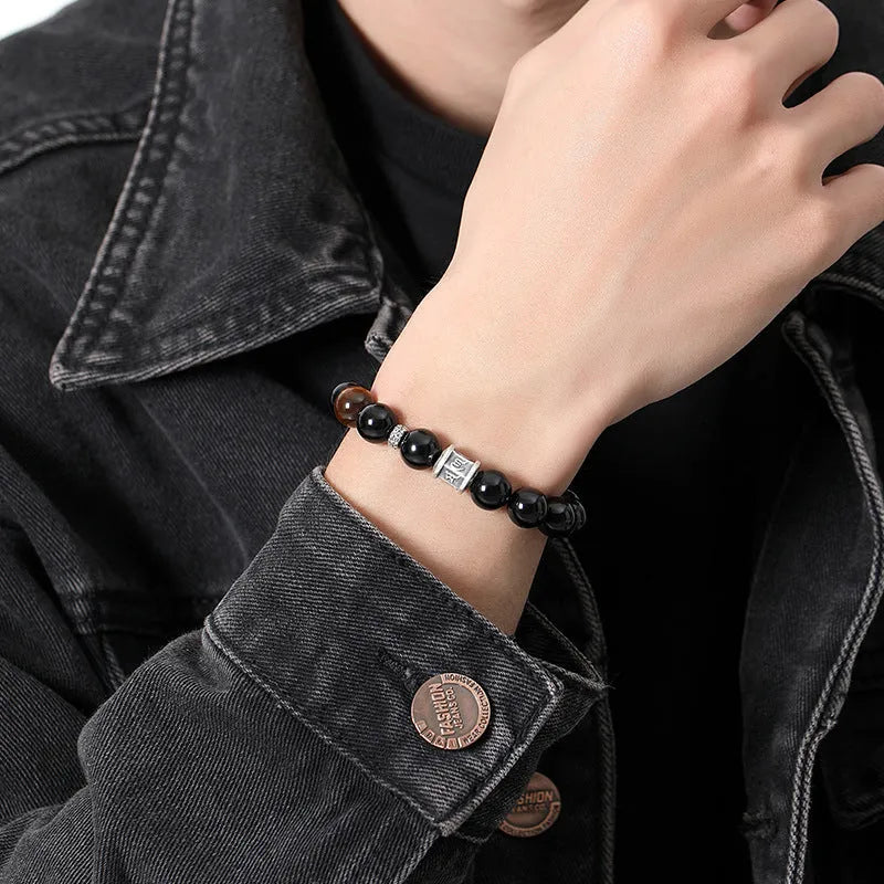Mens black obsidian bracelet with silver prayer wheel charm on wrist