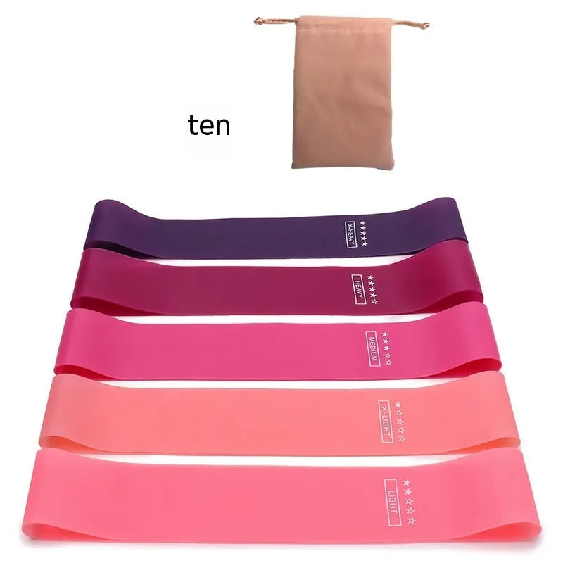 Set of five coloured TPE yoga tension straps for fitness training laid flat showing green, blue, yellow, red, and black.