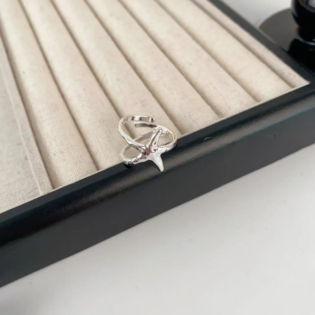 Three-dimensional zinc alloy jasmine flower ring with open mouth design on a finger.