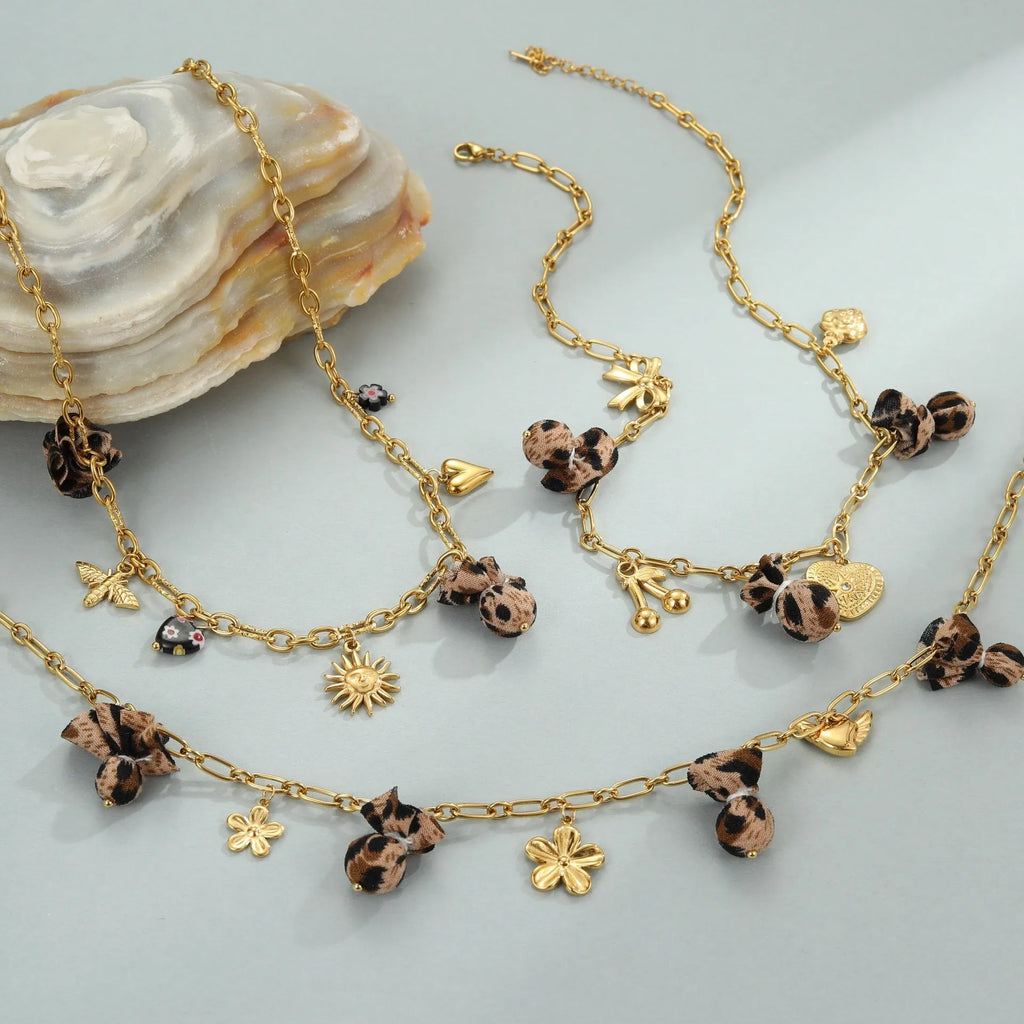 Stainless steel necklace with gold electroplated pendant showing leopard and heart flower designs