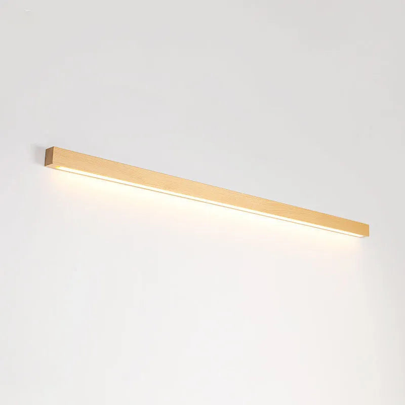 Walnut colour wood and acrylic strip wall lamp in three lengths on a white wall.
