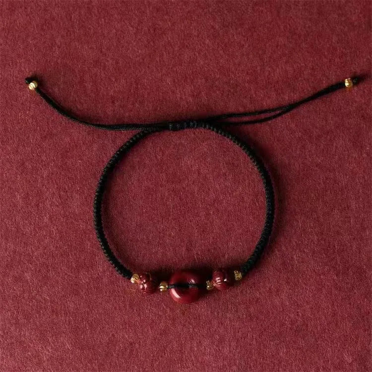 Traditional Chinese cinnabar bracelet with heart-shaped centrepiece and peace buckle clasp on coloured rope cord