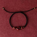 Traditional Chinese cinnabar bracelet with heart-shaped centrepiece and peace buckle clasp on coloured rope cord