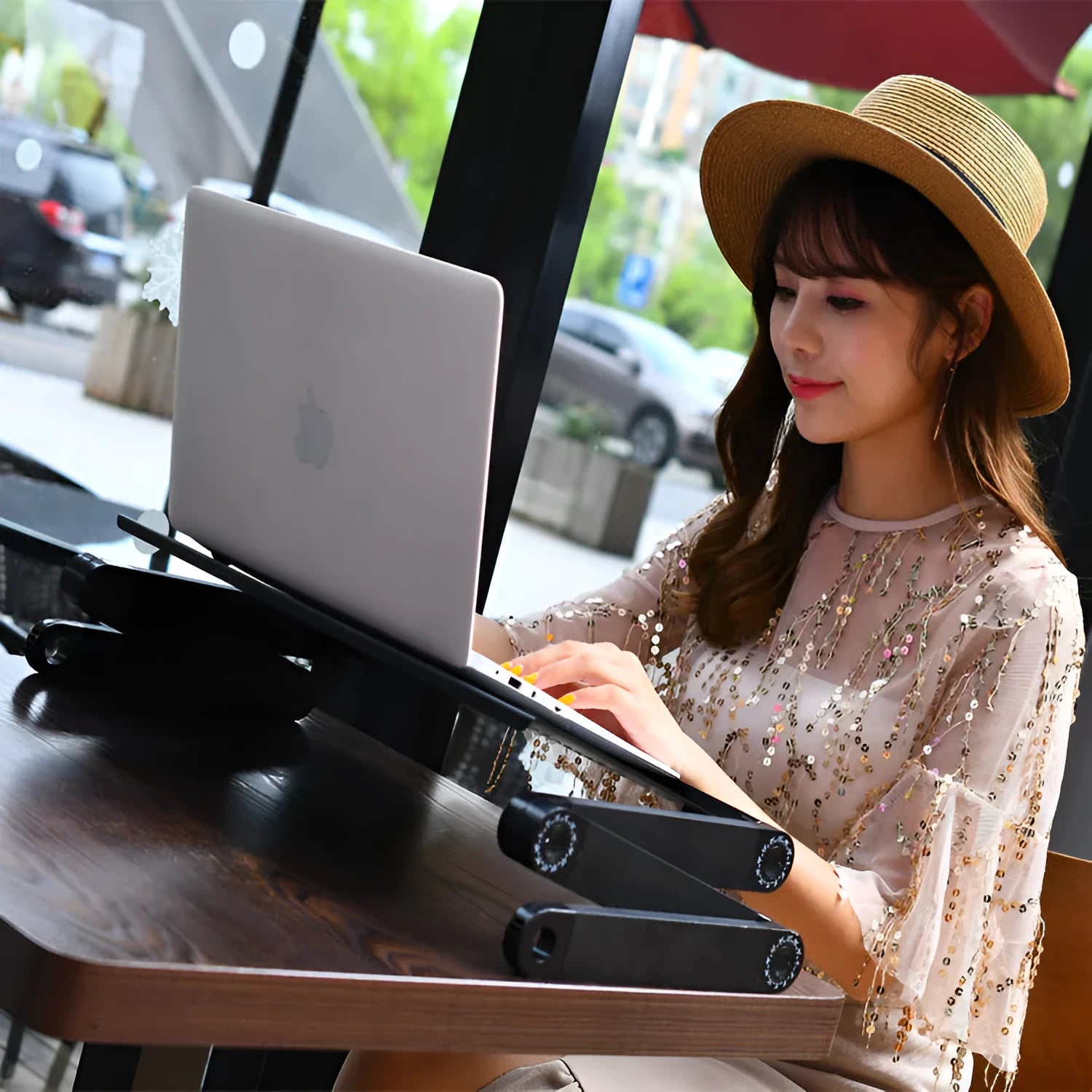 Red folding metal bed desk for laptop with cooling fans, shown in use on a sofa.