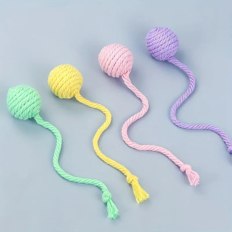 Green cat toy ball with attached rope and internal bell next to a pink one.