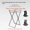 Black outdoor folding trash rack with wooden handle holding a white bin bag open.