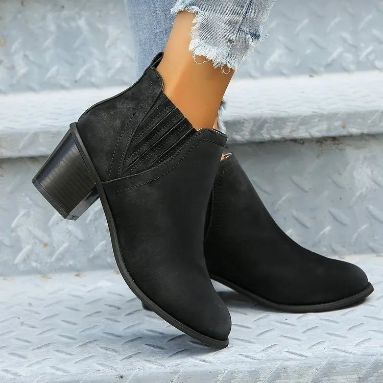 Black women's slip-on ankle boots with a pointed toe and a thick, low square heel on a rubber sole.