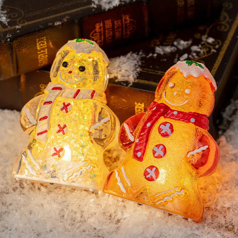 Glowing LED gingerbread man and snowman Christmas ornaments with coloured scarves on a festive tree branch.