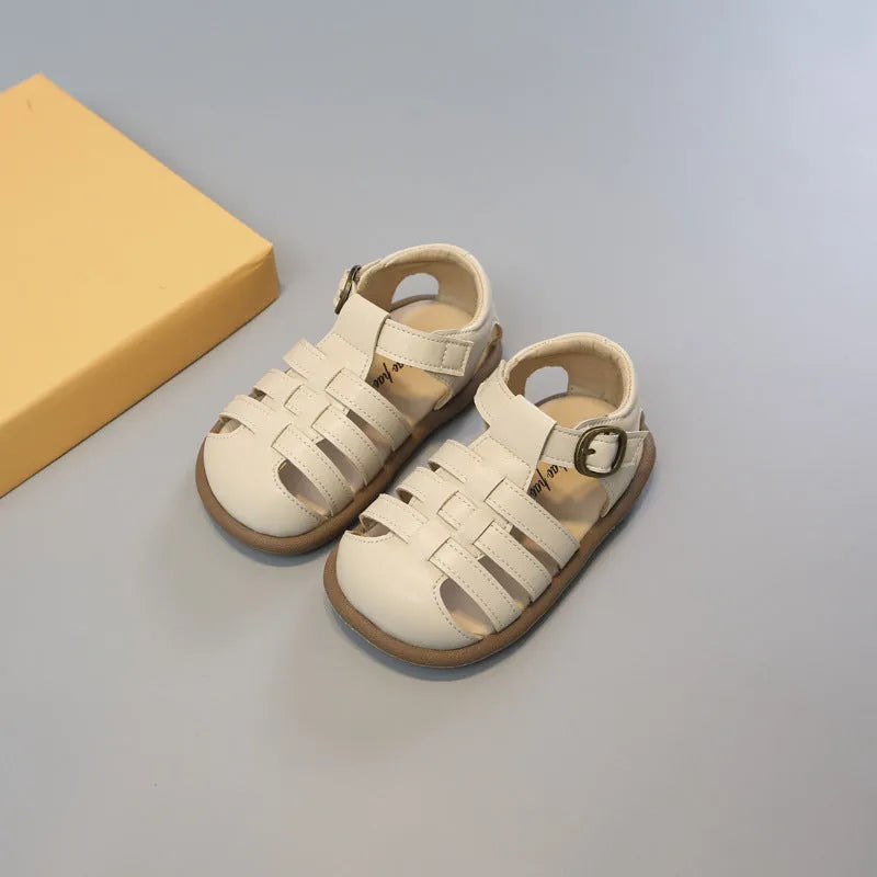 Girls' closed toe PU leather woven hollowed Roman sandals with Velcro strap, beige colour, on toddler feet