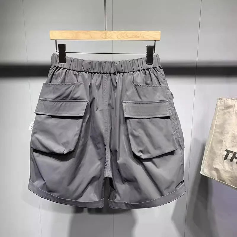 Men's solid black loose-fit work shorts with pockets, shown above the knee.