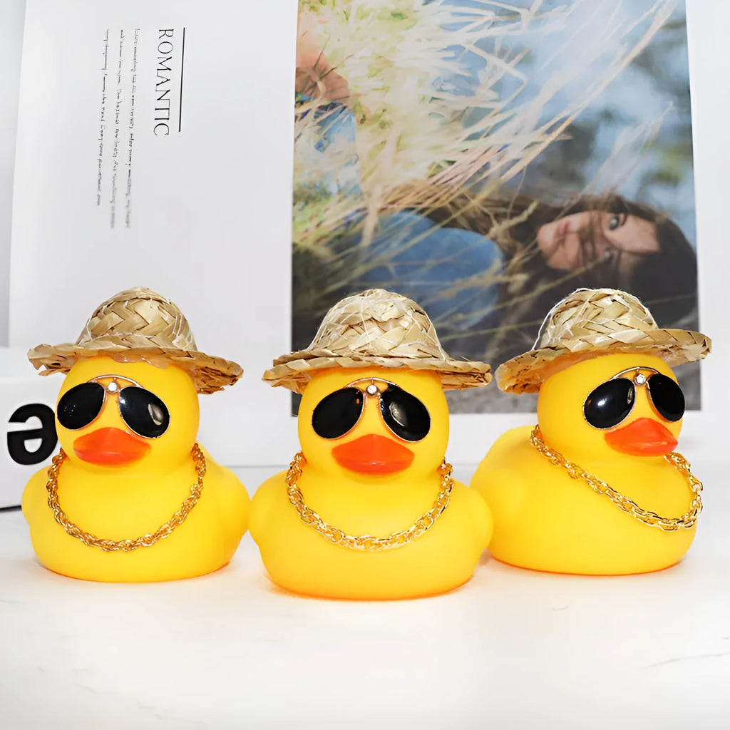 Yellow cartoon duck car ornament wearing a straw hat, with miniature sunglasses accessory.