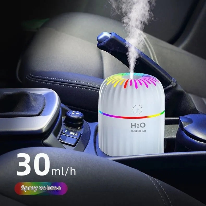Mini car-shaped USB aromatherapy humidifier in green, pink, or white colours on a desk.