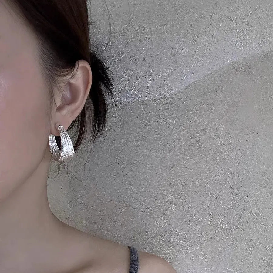 Set of geometric multi-layer earrings in gold and silver, showing stud and clip styles on a flat surface.