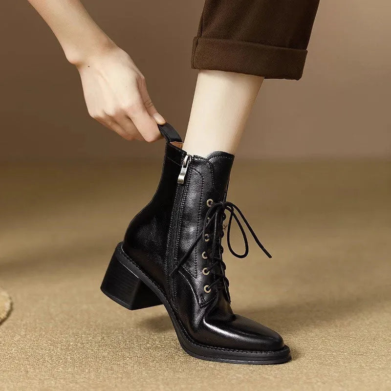 Women's black pointed-toe short tube ankle boots with a low block heel on a neutral background.