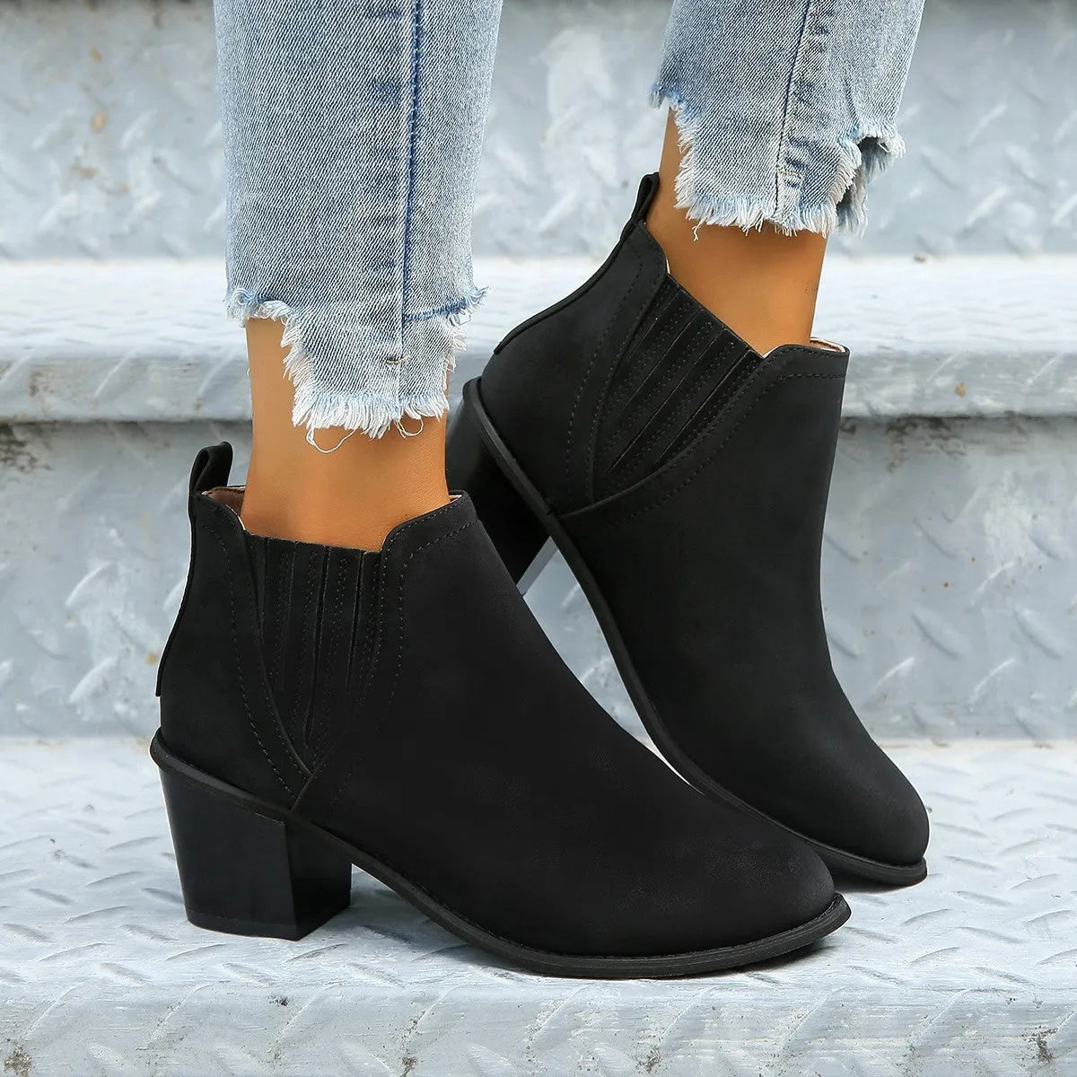 Black women's slip-on ankle boots with a pointed toe and a thick, low square heel on a rubber sole.