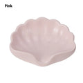 White shell-shaped plastic soap dish for bathroom use on a countertop.