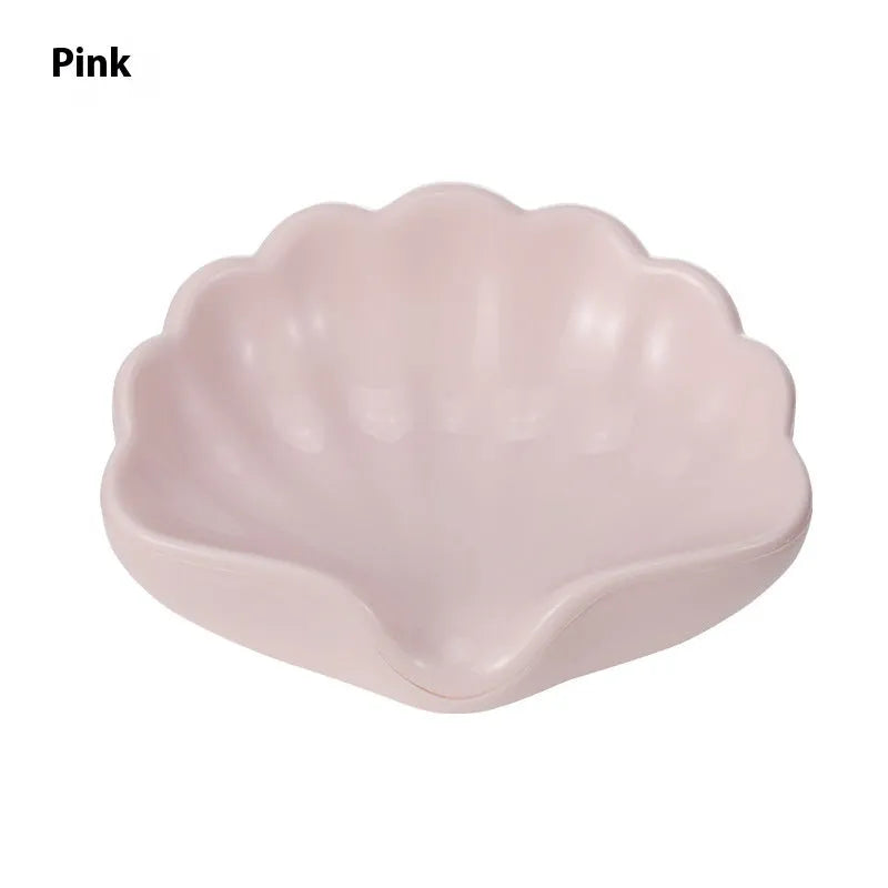 White shell-shaped plastic soap dish for bathroom use on a countertop.