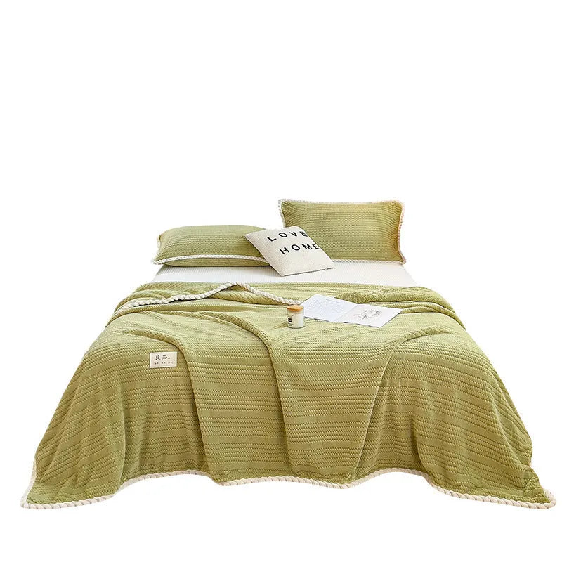 Solid colour jacquard milk velvet blanket in cream white, folded on a sofa, showing textured weave pattern
