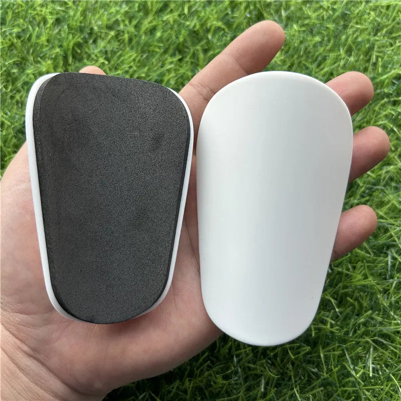Extra small mini football shin guards measuring 8cm by 5cm in black and white plastic