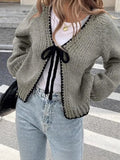 Grey lace-up sweater cardigan with long sleeves and crocheted flower decoration on the front.