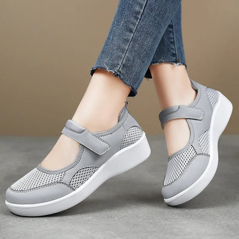 Women's grey breathable mesh slip-on shoe with Velcro strap, flat heel, and round toe.
