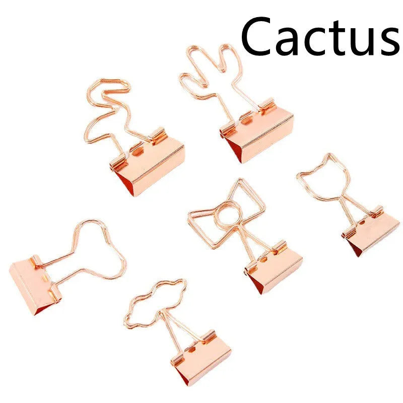 Small gold metal office clip with a long tail handle, shown in decorative bow, cactus, cat, flamingo, and love shapes.