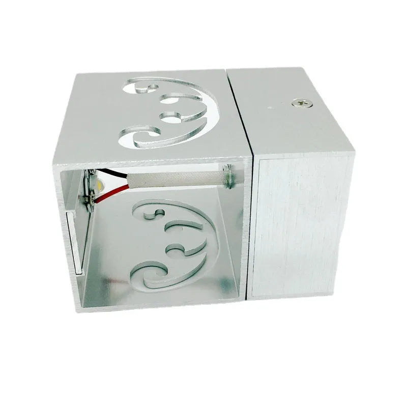 Modern aluminium butterfly-shaped LED wall lamp on a white wall with remote control.