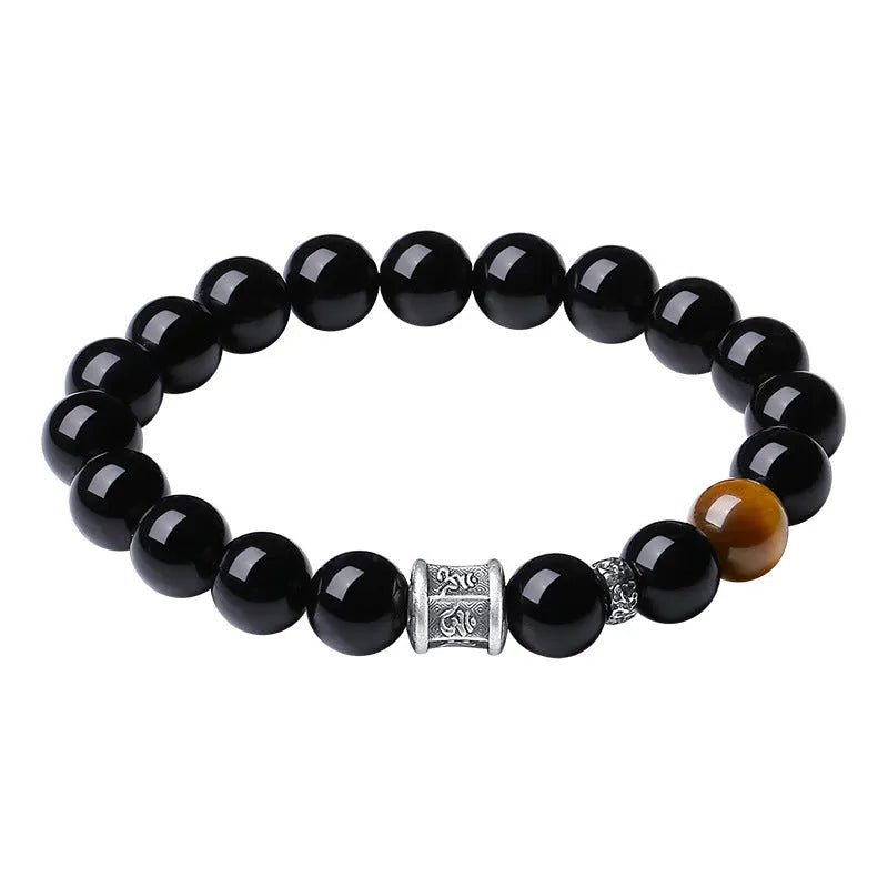 Mens black obsidian bracelet with silver prayer wheel charm on wrist